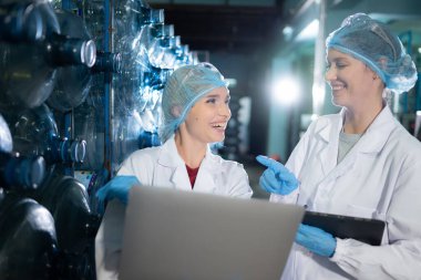 İki genç kadın bilim adamı içme suyu fabrikasında tablet bilgisayarla çalışıyor.