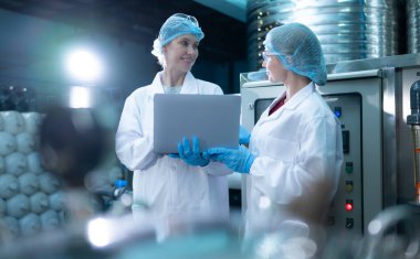 İki genç kadın bilim adamı içme suyu fabrikasında tablet bilgisayarla çalışıyor.