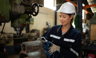 Makine mühendislerinin portresi, bir süredir kullanılan eski bir makinenin çalışma koşullarını kontrol ediyor. Doğal ışığın işyerinde parladığı bir fabrikada.