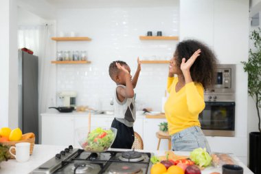 Afro-Amerikan anne ve oğlu salatayı evde birlikte hazırlıyorlar.