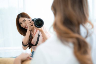 Güzel Asyalı kadın fotoğrafçı evde profesyonel kamerayla fotoğraf çekiyor.