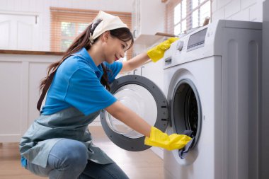 Asyalı genç kadın mutfakta çamaşır makinesini temizliyor. ev işi kavramı
