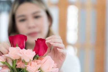 Çiçekçide elinde bir buket gül tutan Asyalı güzel bir kadın..