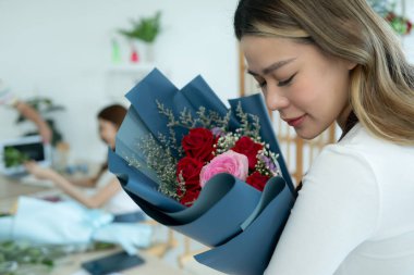 Çiçekçide elinde bir buket çiçek tutan güzel Asyalı kadın.