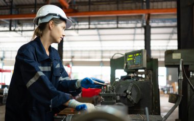 Makine mühendislerinin portresi, bir süredir kullanılan eski bir makinenin çalışma koşullarını kontrol ediyor. Doğal ışığın işyerinde parladığı bir fabrikada.