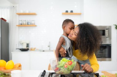 Afro-Amerikan anne ve oğlu salatayı evde birlikte hazırlıyorlar.