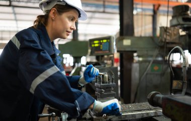 Makine mühendislerinin portresi, bir süredir kullanılan eski bir makinenin çalışma koşullarını kontrol ediyor. Doğal ışığın işyerinde parladığı bir fabrikada.