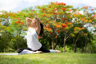 Şehir parkında açık hava aktiviteleri yapan genç bir kadın. Yoga onun seçtiği bir aktivite..