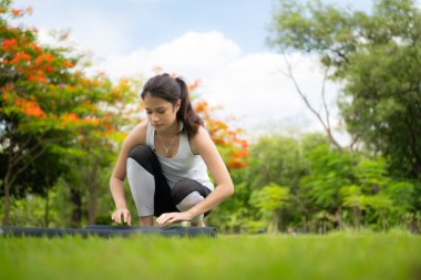 Şehir parkında açık hava aktiviteleri yapan genç bir kadın. Yoga onun seçtiği bir aktivite..