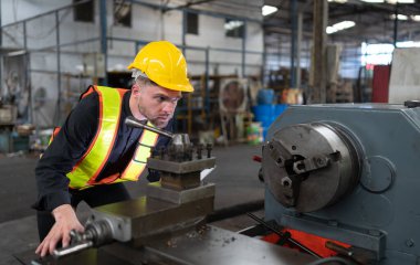 Makine mühendisleri, deponun personeliyle kullanılmış makineleri kontrol etmek ve onarmak için eski makine deposuna girerler..