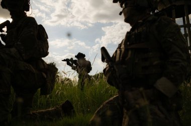 Kamuflajlı özel kuvvetler askerleri modern teknolojiyle dolu ve savaşa hazır bir çift silahla.