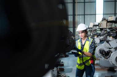 Kadın bir mühendis robot deposundaki robot koluna bir program yüklüyor. Makineyi müşteriye göndermeden önce işlemi test edin.