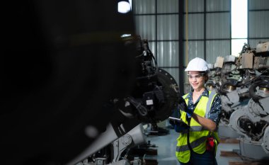 Kadın bir mühendis robot deposundaki robot koluna bir program yüklüyor. Makineyi müşteriye göndermeden önce işlemi test edin.