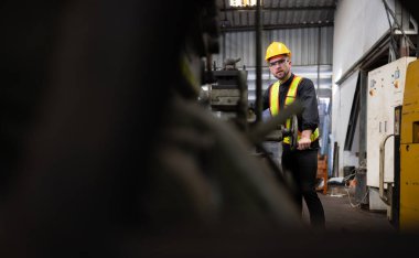 Makine mühendisleri, deponun personeliyle kullanılmış makineleri kontrol etmek ve onarmak için eski makine deposuna girerler..