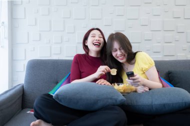 LGBT çifti evlerinin oturma odasındaki kanepede komedi draması izliyor. Çift mutlu bir şekilde güldü..