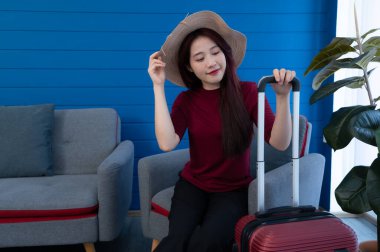 Oturma odasında, Asyalı genç bir kadın kanepede oturur ve hafta sonu gezisine hazırlanır..