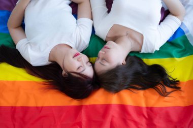 Gökkuşağı bayrağında, bir LGBT çifti mutlu bir şekilde uzanıp sohbet ediyor ve birbirlerine sataşıyorlar..