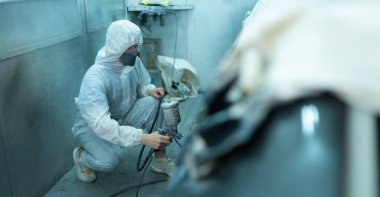 Araba sprey odasındaki oto tamircisi arabanın orijinal rengiyle harmanlanan güzelliği yaratmak için araba gövdesinin kenarına bir sprey enjektör kullan..