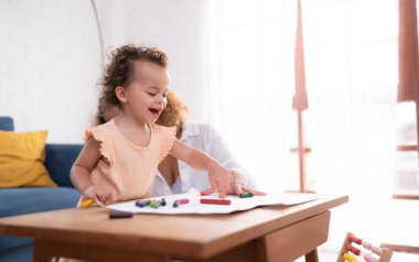 Küçük bir çocuğun hayal gücü renkli kalem çizimleriyle temsil edilir ve anne dikkatle evin oturma odasını denetler..