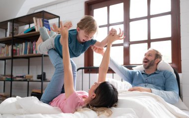 Küçük çocuk annesiyle uçuyor. Yatak odasında yatağının üstünden uçup uçmasına yardım etmek için bacaklarını kullanıyor..