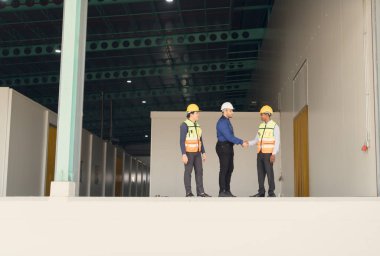 Bir depo müdürü ve iki çalışan büyük bir depodaki rafları nasıl düzenleyeceklerini düşündükten sonra dinleniyorlar..