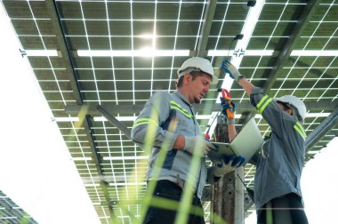 Elektrik mühendislerinden oluşan bir ekip, yüz dönümlük alanın ortasında bulunan bir güneş paneli alanında güneş panellerini inceliyor ve muhafaza ediyor..