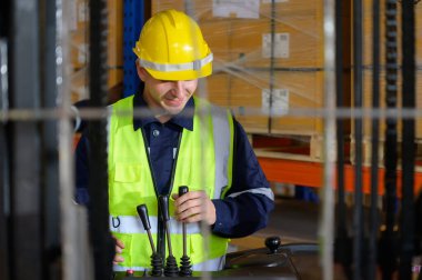 Otomobil parçaları deposunda çalışan işçiler, araba montaj hattına teslim edilmeyi bekleyen deponun deposundaki yedek parça kutusunu getirmek için forklift kullanıyorlar.