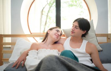 Genç çift sabah yatak odasında, günün farklı görevlerini yapmadan önce mutlu bir şekilde konuşup şarkı söylüyorlar..