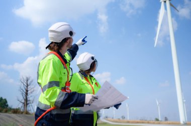 Doğal Enerji Rüzgâr Türbini sahasında görevli kadın ve erkek mühendis. Rüzgar enerjisini elektriğe dönüştüren büyük rüzgar türbini operasyonlarının günlük denetim görevleriyle