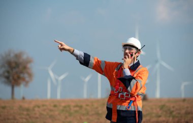 Doğal Enerji Rüzgâr Türbinleri 'nin mühendisi büyük rüzgar türbinlerinin icabına bakmak için rüzgar türbininin tepesinde çalışan bir meslektaşla iletişim kurmak için bir telsiz kullan..