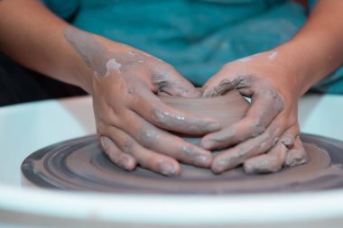 Çömlek sanatçısı, genç bayan mümkün olan en çekici eserleri üretmek için sakince ve titizlikle kilden bir parça yapıyor.,