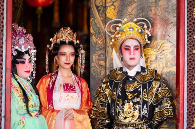 Kutsal bir tapınak ya da tapınağın girişinde geleneksel Çin Yeni Yılı için dua eden erkek ve kadın opera sanatçılarının portresi..