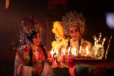 Çinli erkek ve kadın opera oyuncuları, Çin Yeni Yıl Festivali vesilesiyle refahınızı artırmak için tanrılara dua etmek üzere bir mum yakıyorlar..