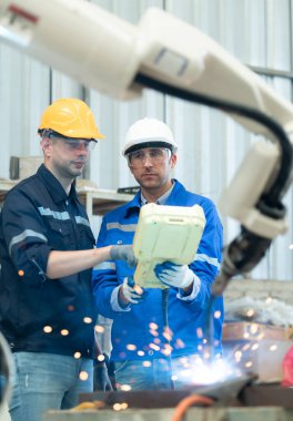 Her iki mühendis de kaynak yapan bir robot eli kullanıyor. Kaynak manipülasyonunu kaynak denetimi için kontrol paneliyle birleştirerek. Hızlı ve güvenli.