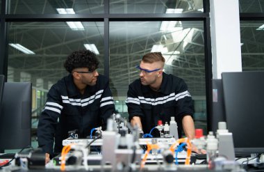 Robotik el teknolojisi öğretmeni yeni öğrencilere çeşitli endüstriyel uygulamalar için elektronik devre kartlarının ve robot el komutlarının nasıl kullanılacağını öğretiyor..