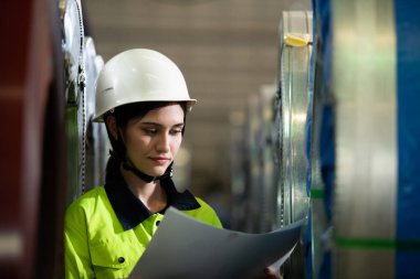 Metal levha fabrikasının makinelerini incelemeye gelen büyük bir endüstriden kadın mühendisin portresi..