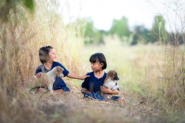 Tayland 'ın kırsalında, küçük kızlar birlikte oynarlar neşeyle gülerler ve evcil köpeklerle oynarlar.