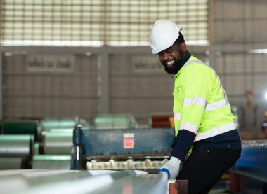 Genç mühendisler, metal levha döşemeleri üreten fabrikadaki makinelerin istenildiği gibi çalıştığını test ediyor ve doğruluyor.