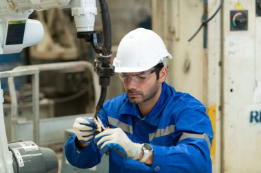 Deneyimli genç erkek mühendisler kaynak robotlarının işlevselliğini sürdürüyor ve test ediyorlar. Kaynak robotlarının sıkı çalışmasından sonra