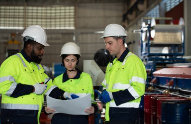 Young female engineer learning to run machinery at a factory with veteran engineers on hand to offer guidance and assistance. clipart