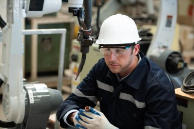 Deneyimli genç erkek mühendisler kaynak robotlarının işlevselliğini sürdürüyor ve test ediyorlar. Kaynak robotlarının sıkı çalışmasından sonra