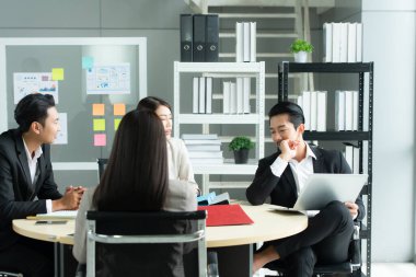 Bir grup genç Asyalı girişimci. Top Management, ekipten gelen yatırım verilerini gözden geçirmek için doğal ışık pencereli bir toplantı odasında toplanıyor..