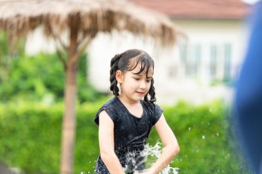 Toplum sahasında çamur kaydırağı oynayarak eğlenen çocuklar. Aileler uzaktan izlerken.