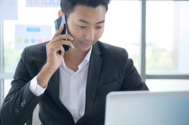 Çağrı merkezinde çalışan Asyalı genç bir adam, danışman arayan müşterilerle hisse senedi yatırım bilgileri üzerine danışmanlık yapıyor.