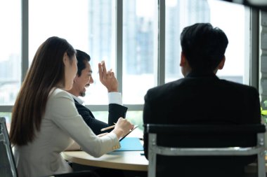 Bir grup genç Asyalı girişimci. Top Management, ekipten gelen yatırım verilerini gözden geçirmek için doğal ışık pencereli bir toplantı odasında toplanıyor..