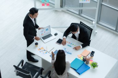 Bir grup genç Asyalı girişimci. Top Management, ekipten gelen yatırım verilerini gözden geçirmek için doğal ışık pencereli bir toplantı odasında toplanıyor..