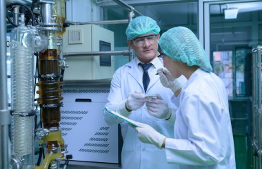 Bilim adamları ve asistanlar makine dairesinde yağ ve kenevir tohumları çıkarıyorlar. Hazırlanmış kenevirleri ayırmaya başlamadan önce kenevir yağı çıkarıcısını denetlemek