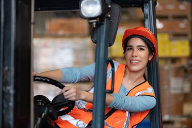Depoda ağır eşyaları kaldırmak için forklift kullanan Asyalı bir kadının portresi..