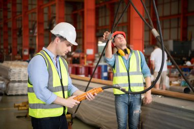 İki genç mühendis, fabrikadaki vinç operasyonunu test ediyor ve kontrol ediyor..