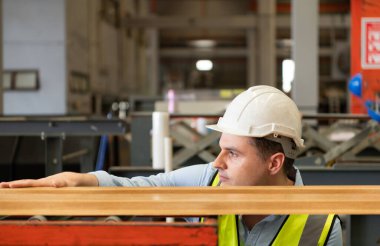 İki genç mühendis, fabrikada metal levha oluşturan makinelerin çalışmasını test ediyor ve doğruluyor.